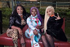 three women sitting on a red bench posing for the camera