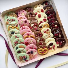 a box filled with lots of different flavored donuts on top of a table