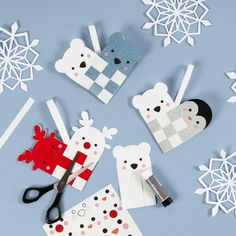 paper cut out animals and snowflakes on a blue surface with scissors in the foreground