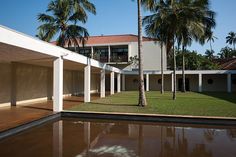 an empty swimming pool in front of a building with palm trees on the lawn and water running through it