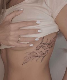 a woman's stomach with a tattoo design on the side and her hand resting on it