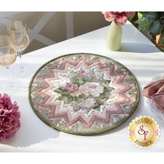 a table topped with a plate covered in flowers next to wine glasses and vases