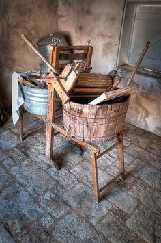 an old wooden bucket sitting on top of a table next to a metal pail