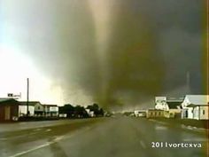 a very large cloud is in the sky over some houses and buildings on a street