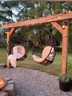 two hanging chairs in front of a fire pit