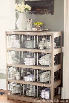 a shelf filled with baskets next to a white vase on top of a hard wood floor