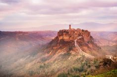 a castle on top of a mountain with fog in the air and trees around it