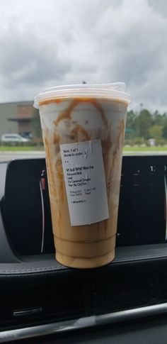 a cup of coffee sitting on top of a car dash board in the back seat