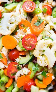 a salad with carrots, cauliflower, cucumbers and tomatoes