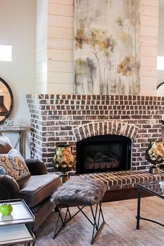 a living room filled with furniture and a fire place in front of a brick fireplace