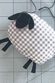 a black and white sheep sitting on top of a piece of paper next to scissors