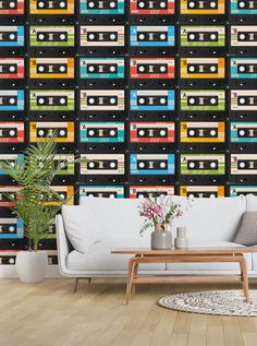 a living room with a couch, table and wallpaper that has cassette tapes on it