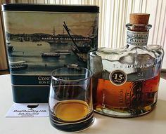 a bottle and glass sitting on a table next to a box with a ship in it