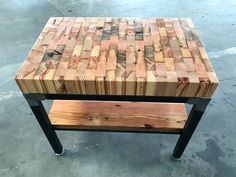 a wooden table sitting on top of a cement floor next to a black metal frame