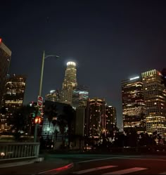 the city skyline is lit up at night with skyscrapers and street lights in the foreground