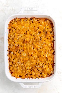 a casserole dish filled with cheese and other toppings on a white surface