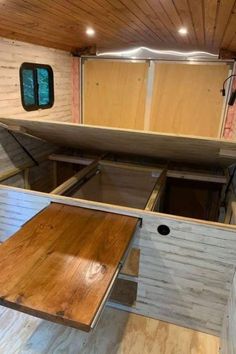 the inside of a camper with wood flooring and storage compartments on each side