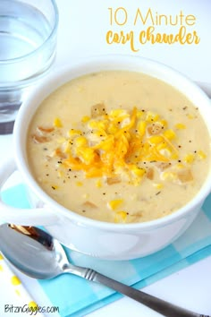 a white bowl filled with corn chowder next to a glass of water and spoon