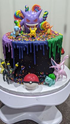 a birthday cake decorated with sprinkles and pokemon figurines on top