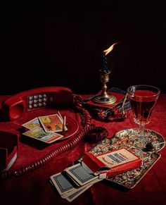 a red phone sitting on top of a table next to a glass filled with liquid