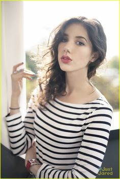 a woman in striped shirt leaning against a wall