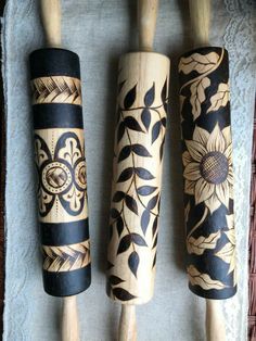 three wooden utensils with floral designs on them sitting on a towel next to each other