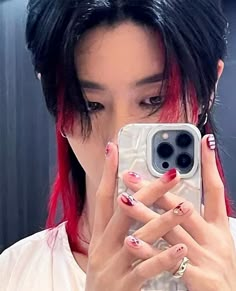 a woman with red and black nail polish holding a cell phone in front of her face