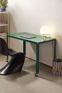 a green table and chair in a room with a lamp on the wall next to it