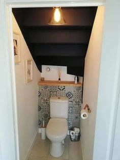 a white toilet sitting inside of a bathroom next to a wall mounted light above it