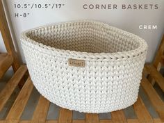 a white crocheted basket sitting on top of a wooden floor next to a sign