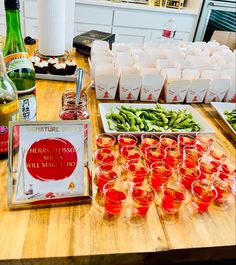 there are many glasses on the table with food and drinks around it, including green beans