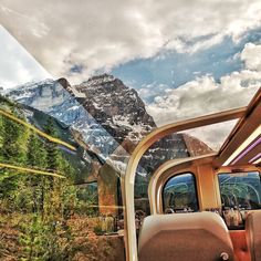 the interior of a vehicle with mountains in the background and clouds in the sky above