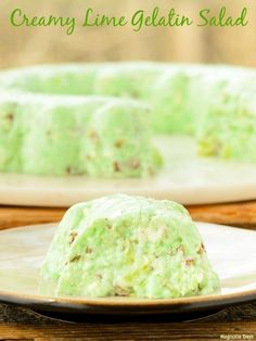 a green cake sitting on top of a plate next to a white plate with a piece of cake covered in frosting