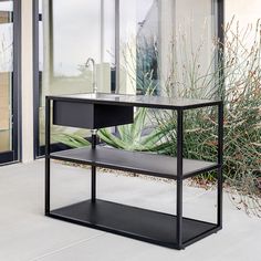 a black shelf sitting on the side of a building next to a plant and glass door