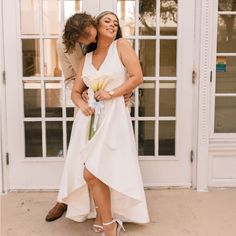 a woman in a white dress is hugging a man