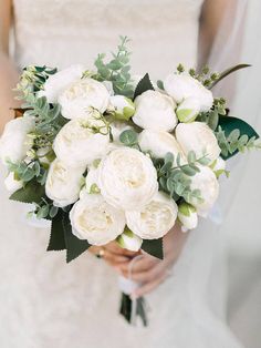 a bride holding a bouquet of white flowers