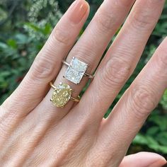 a woman's hand with two engagement rings on her fingers and one ring in the middle