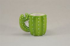 a green ceramic cactus mug with white dots on the rim and handle, sitting in front of a gray background