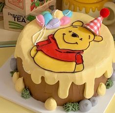 a winnie the pooh birthday cake on a table with other items in the background