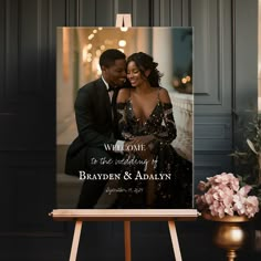 a couple is posing in front of a welcome sign with their wedding date printed on it