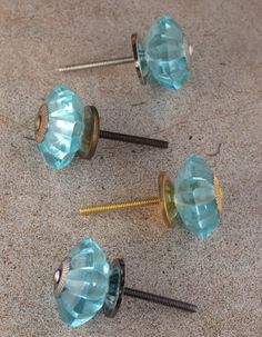 three blue glass knobs and two screws on the ground