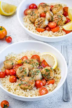 two white bowls filled with shrimp and rice topped with cherry tomatoes, lemon wedges and parsley