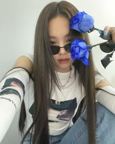 a girl with long hair wearing sunglasses and holding a blue rose