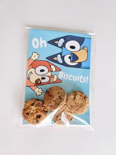 two cookies wrapped in plastic on top of a white table with an image of cartoon characters