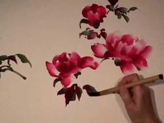 a person holding a pencil and drawing flowers on the wall