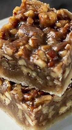 two pieces of pecan bar sitting on top of a white plate