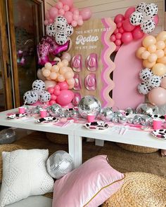 a table topped with lots of pink and white balloons next to a sign that says hello kitty