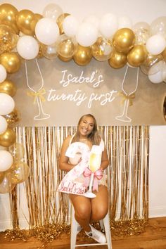 a woman sitting on a stool in front of balloons