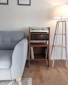 a living room with a gray couch and a wooden side table next to a lamp