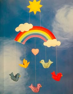 a rainbow mobile with birds and hearts hanging from it's strings in the sky